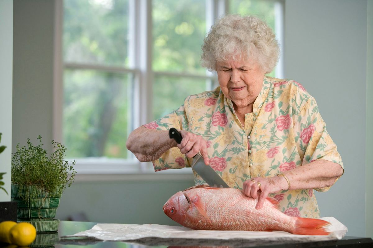 An elderly woman cooking independently in her own kitchen